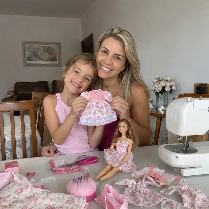 Mãe e filha costurando roupinhas para bonecas em casa